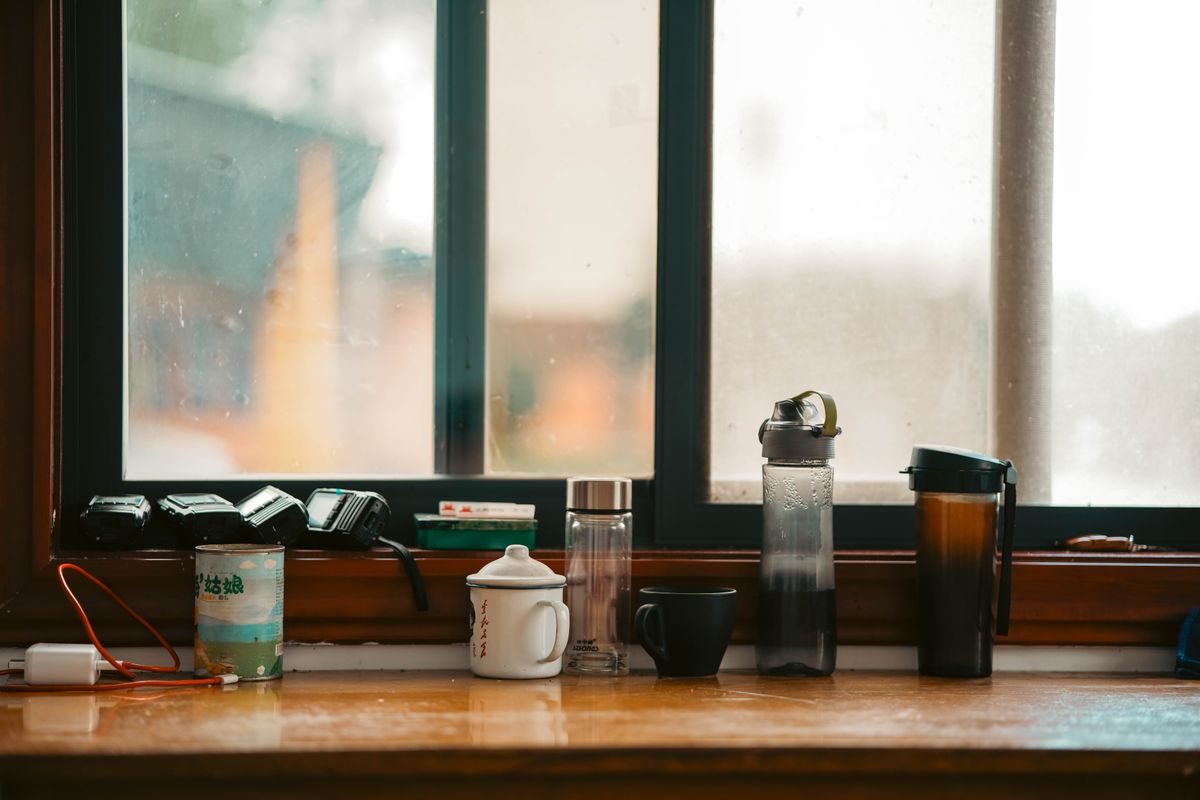 Various mugs and bottles on a window sill, showcasing an everyday indoor scene.