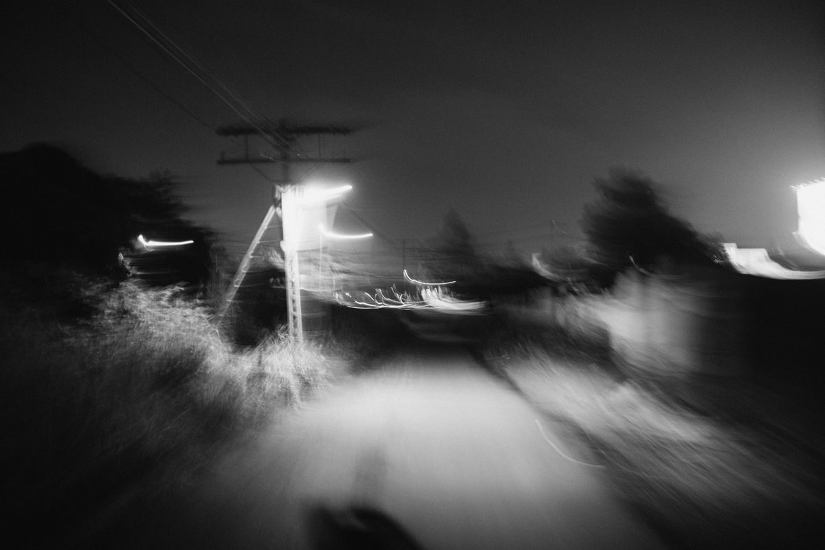 Abstract black and white image of a blurry road at night with streetlights.
