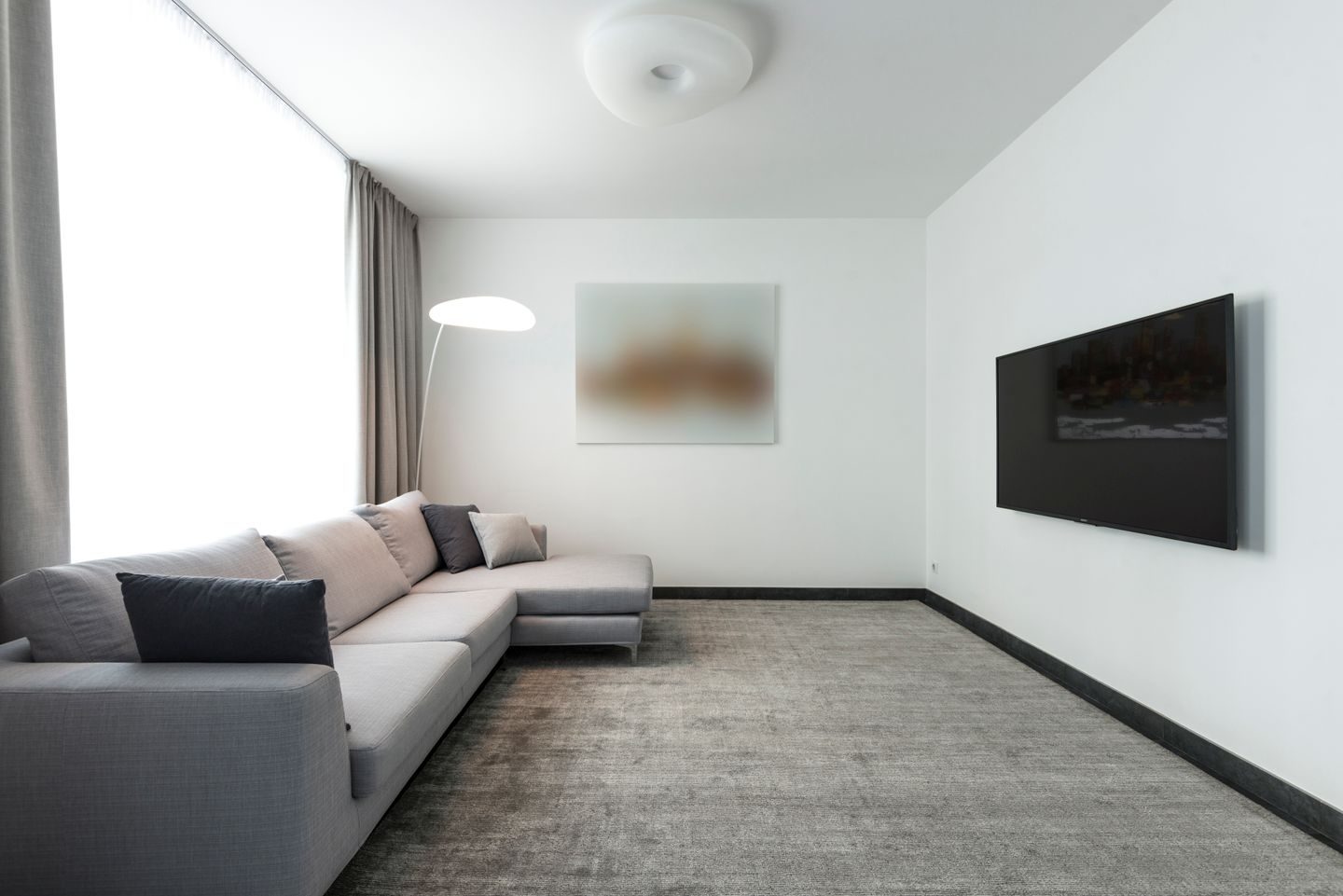 A contemporary living room with a gray sectional sofa and a wall-mounted TV