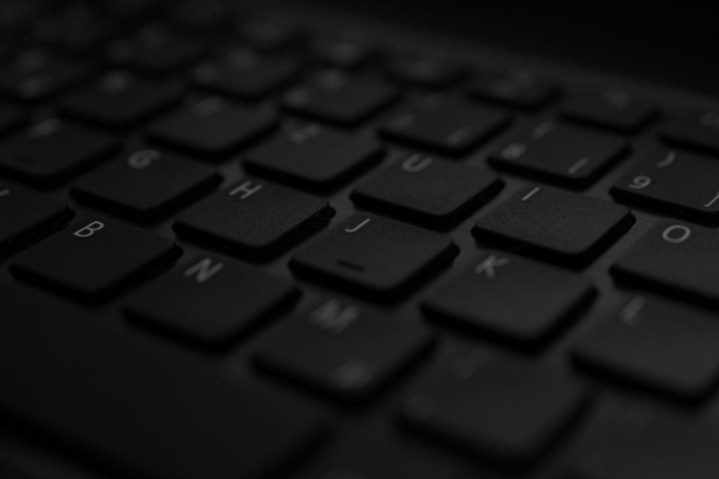 Photograph: A detailed close-up of a black laptop keyboard with soft lighting and selective focus.