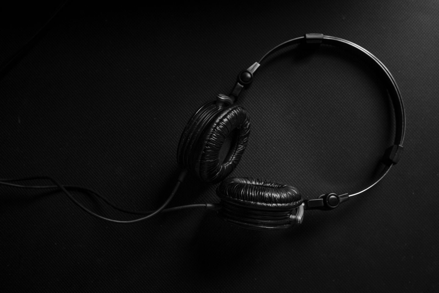 Photograph: Minimalist black headphones on a dark textured background, ideal for audio and music design themes.